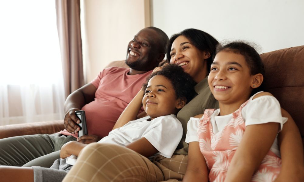 Parents and kids sitting in loungeroom watching tv together 